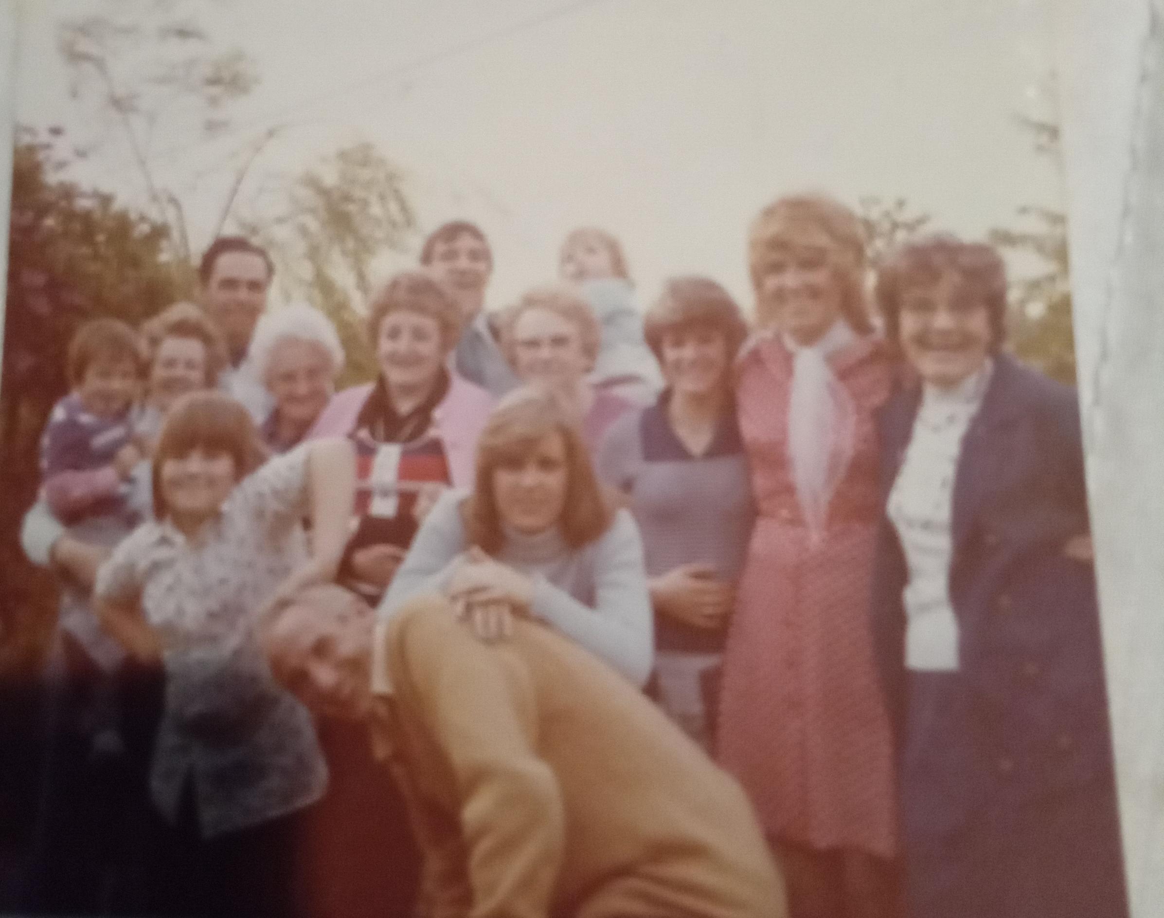 Bird (red dress) with family in England. Uncle Bob is leaning over and cousin Janis Pownell is resting on him. Paul McIntyre is the child with his hand on Uncle Bob