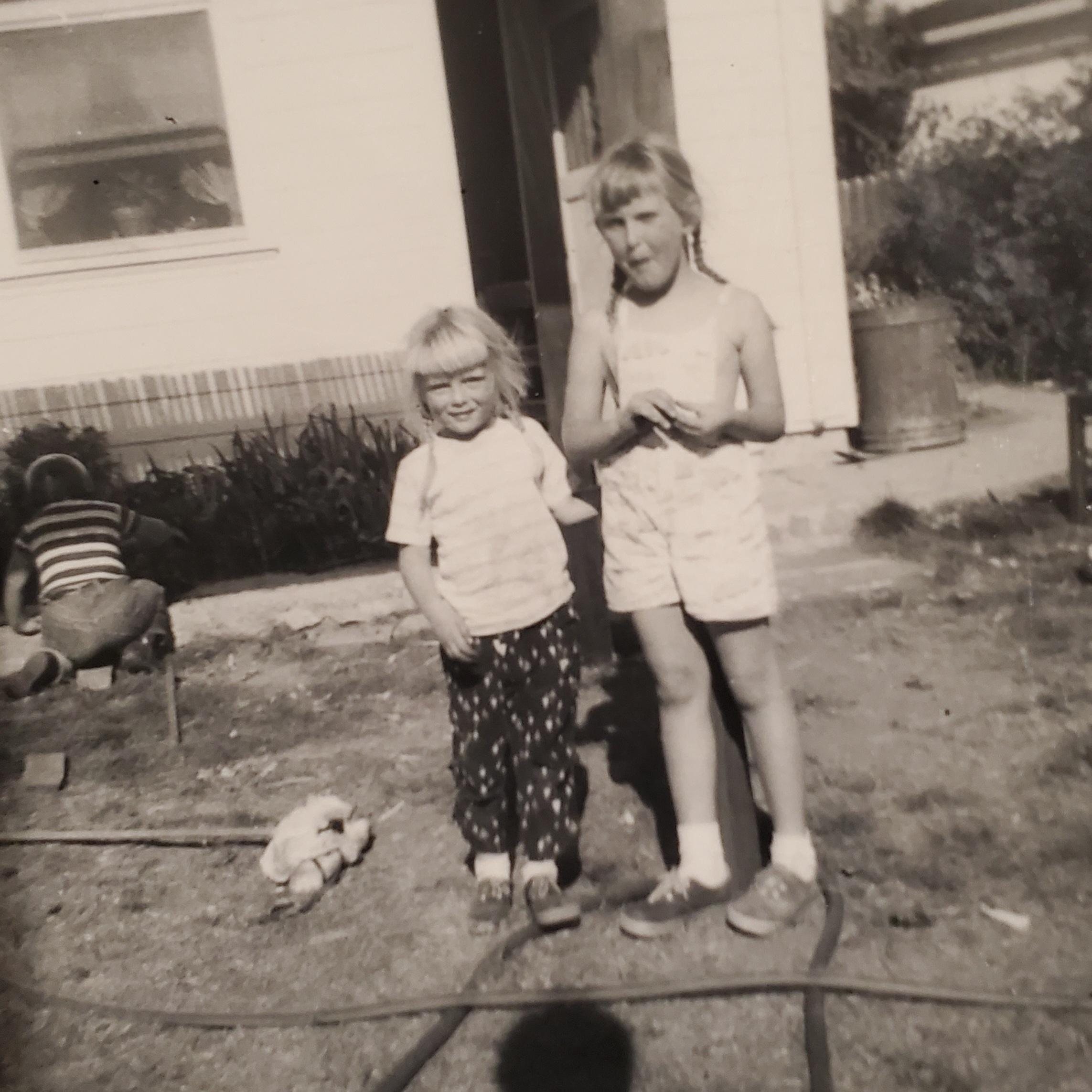 Around 1956- Carole on the right about 6 years old and her pipsqueak little sister Lora on the left about 4 years old. (I think that is Erik in the background). We all loved to create moats, channels and mud puddles whenever we got a chance. 