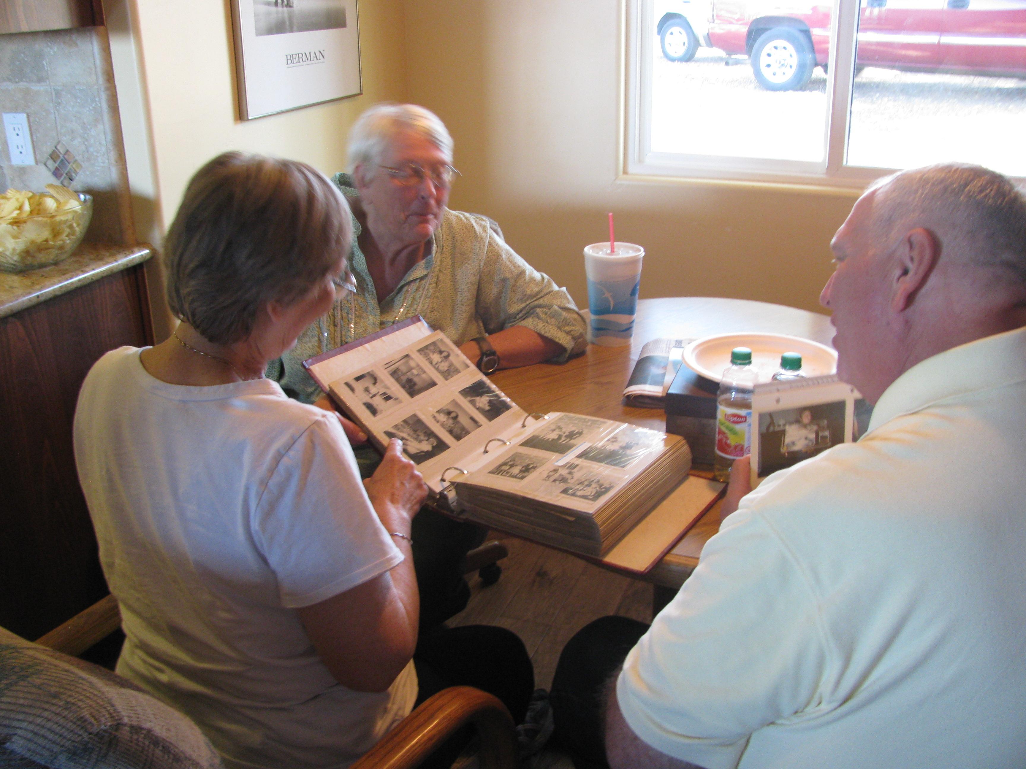 Carole, Sandy, Erik looking at an old Eklund photo book.